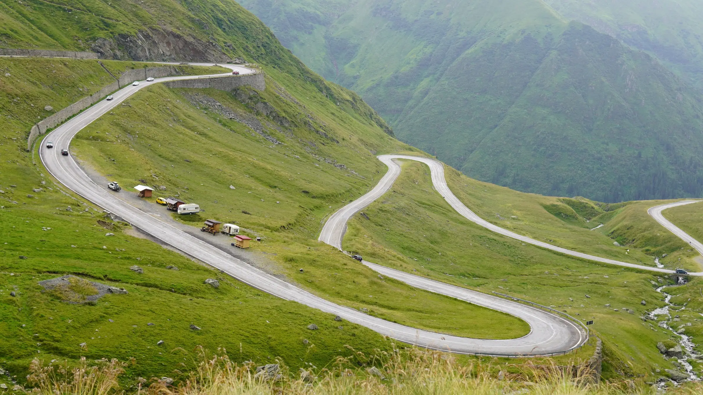 Serpentinele Transfăgărășanului printre pajiști alpine verzi în Munții Făgăraș