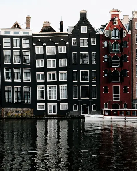 Case înguste pe canal în Amsterdam, oglindite în apă