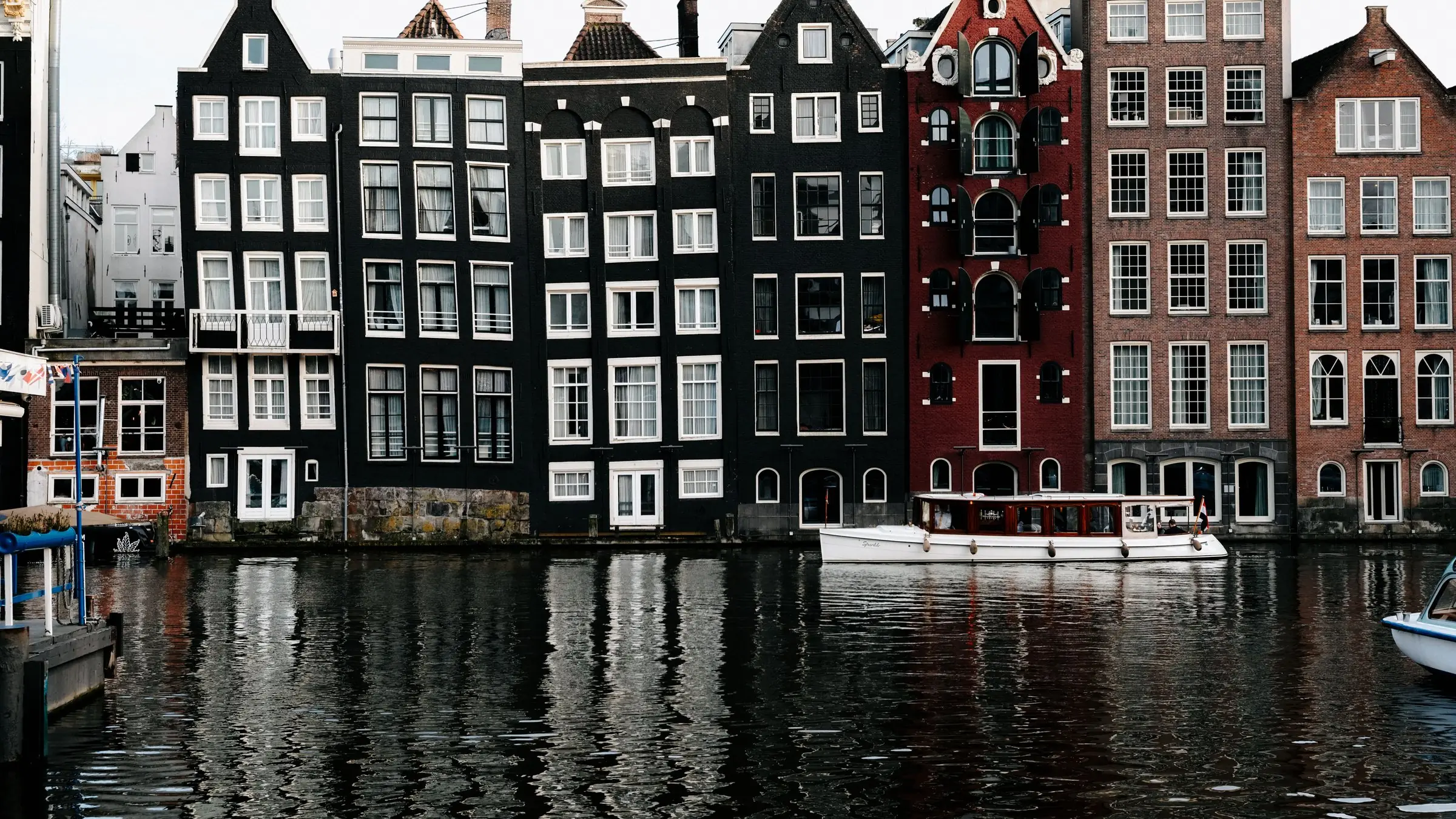 Case înguste pe canal în Amsterdam, oglindite în apă