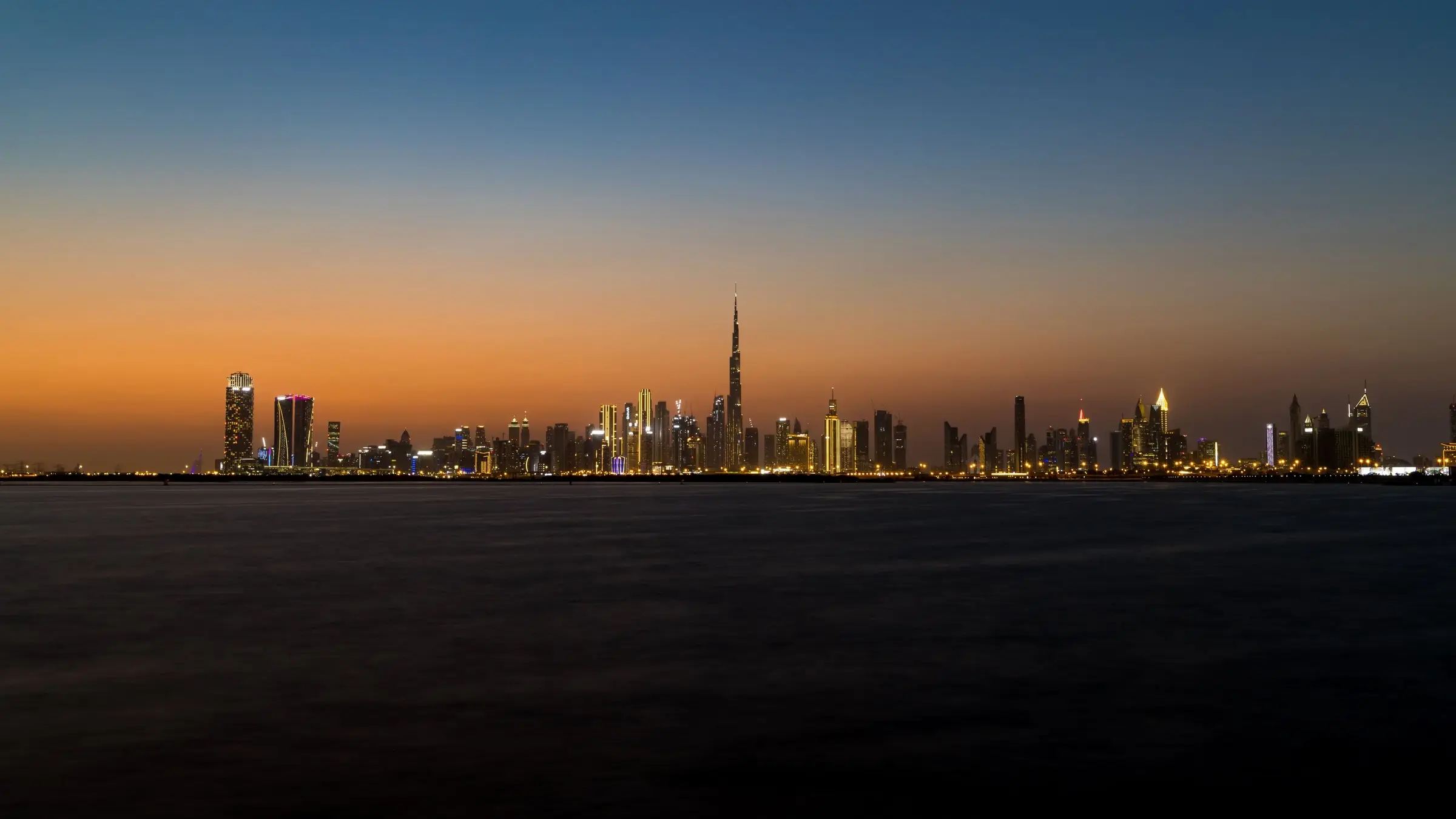 Silueta orașului Dubai cu Burj Khalifa, la amurg, văzută de pe mare