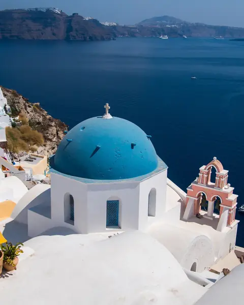 Cupole albastre și case albe în Oia, Santorini, deasupra calderei