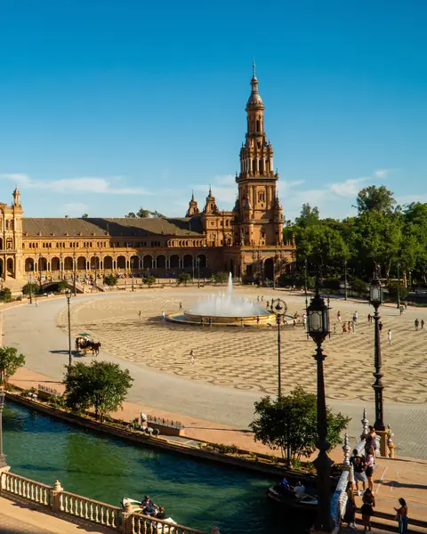 Plaza de España din Sevilla, cu canal, fântână și turn, sub cer albastru