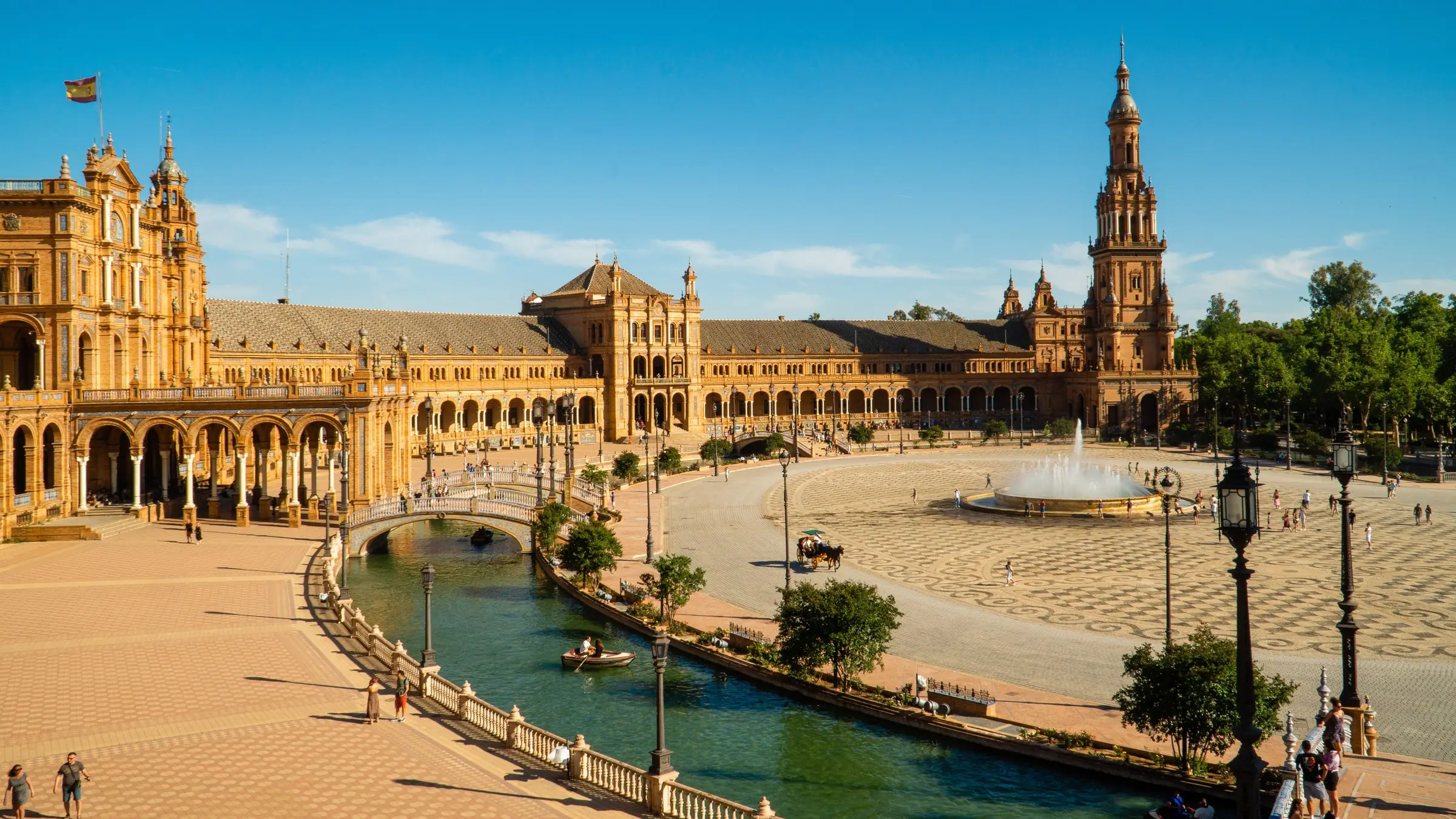 Plaza de España din Sevilla, cu canal, fântână și turn, sub cer albastru