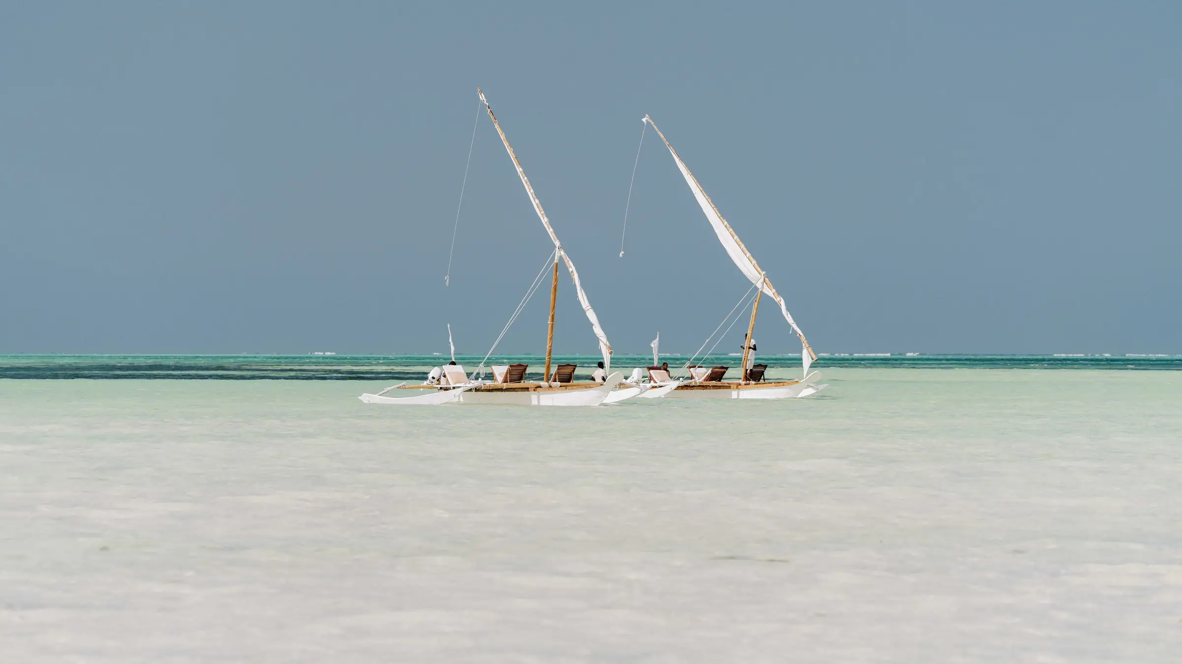 Două bărci tradiționale cu pânze pe laguna puțin adâncă din Zanzibar